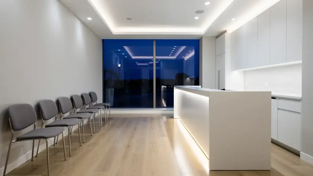 An empty office reception area after hours with aligned waiting chairs and a wiped counter